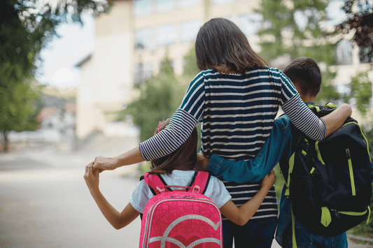 woman with two young children going to school